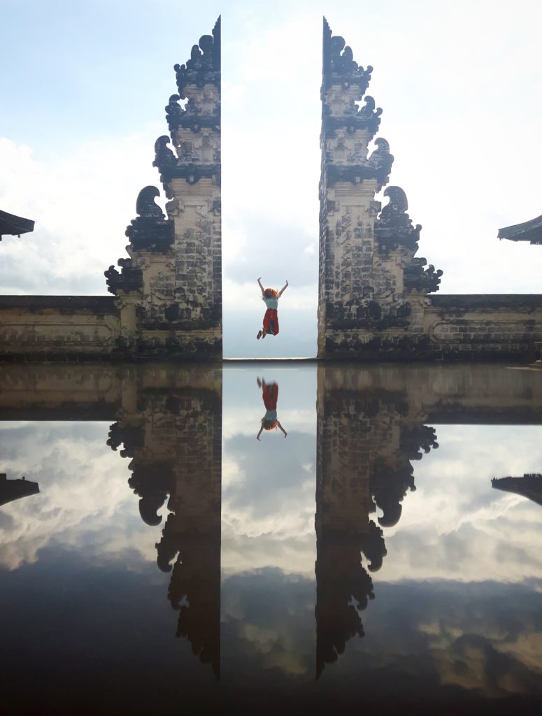 woman jumping in the air in a doorway of a Bali temple