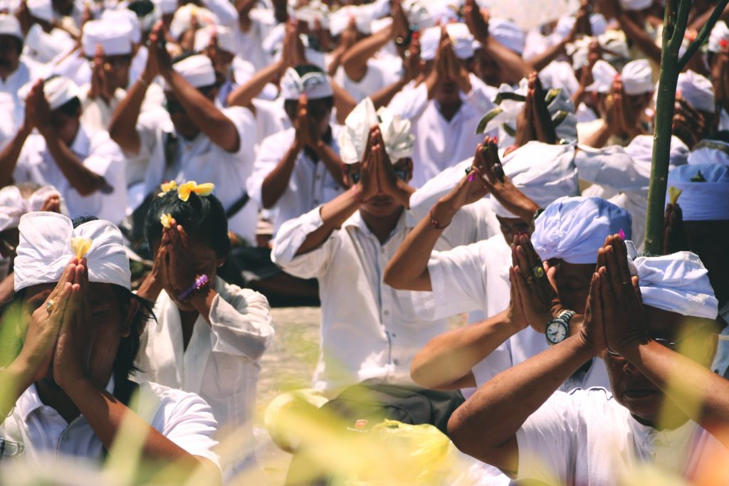 many people wearing white with their hands in prayer