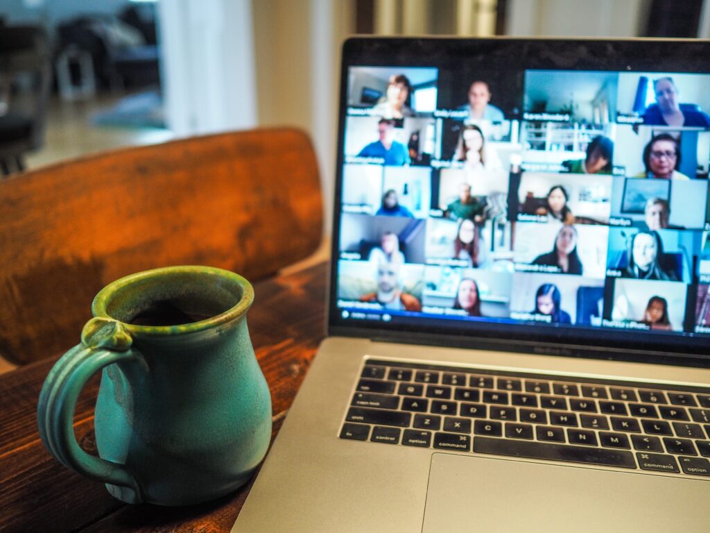 A mug next to a laptop with lots of people on a video call