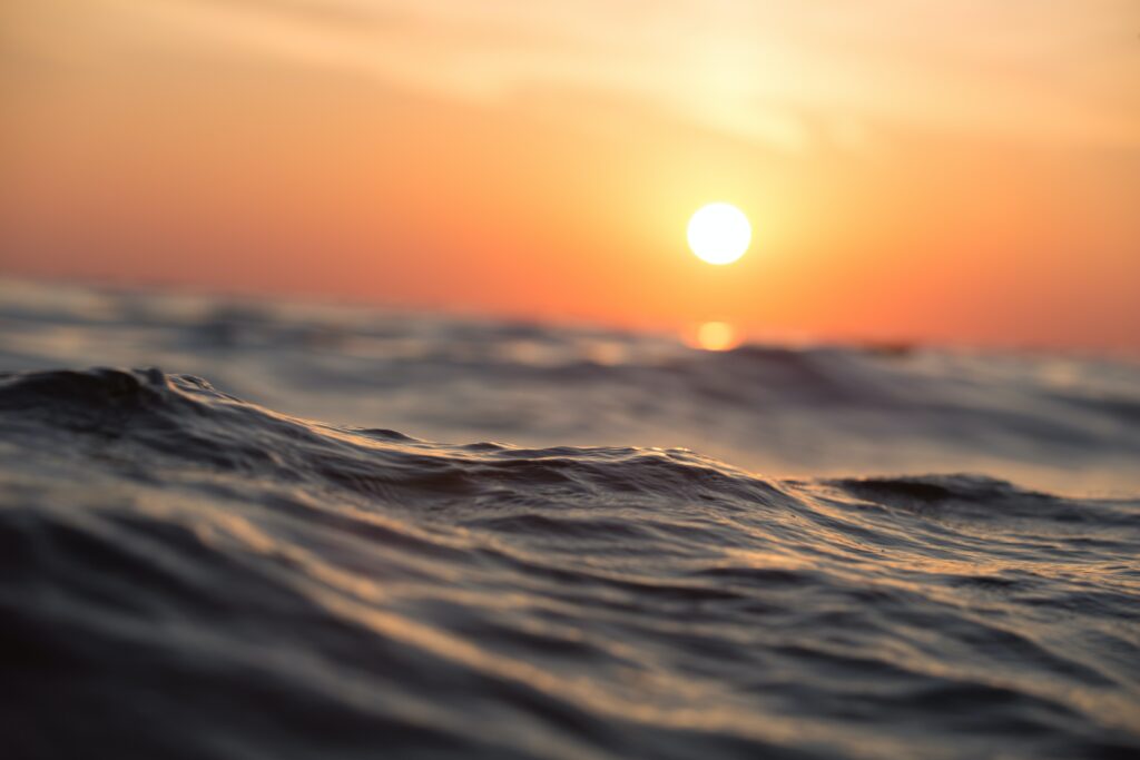 a sunset viewed from between the waves in the sea