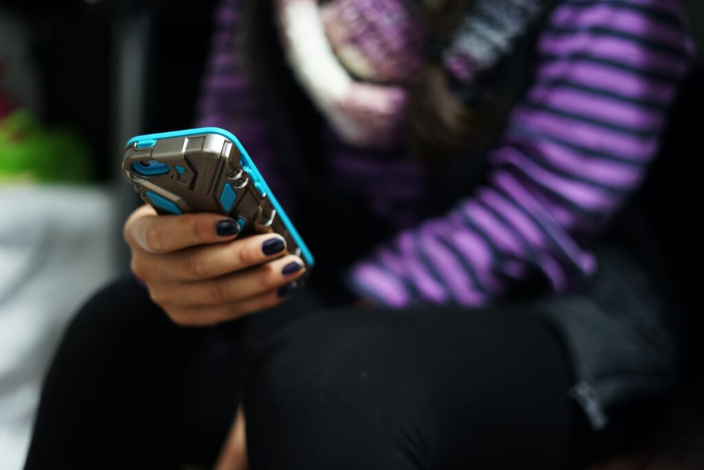 a woman in a purple jacket using a phone in a blue case